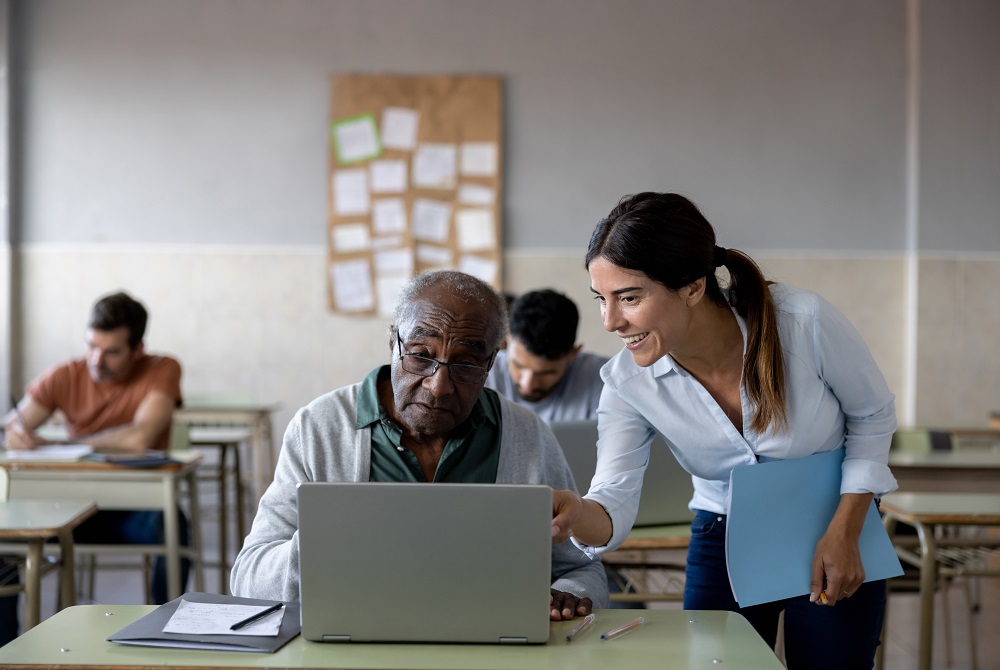 A man and woman seated at a table, reviewing documents and discussing their contents together.